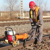 Railway workers are tightening screws with a rail fastener wrench